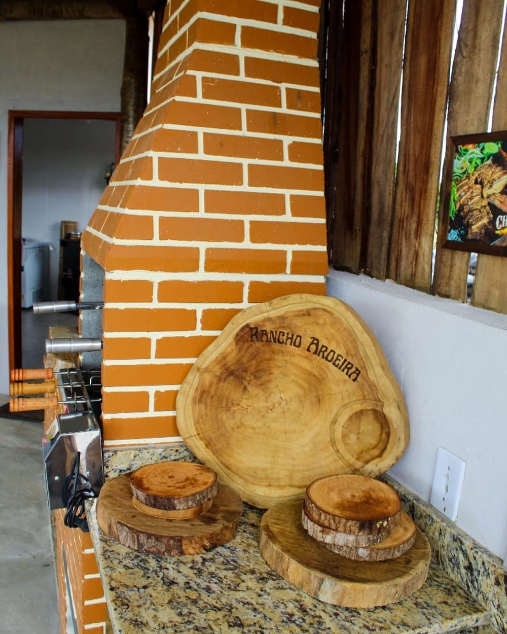 Tábuas de madeira com o nome Rancho Aroeira gravado, ao lado do forno de tijolo