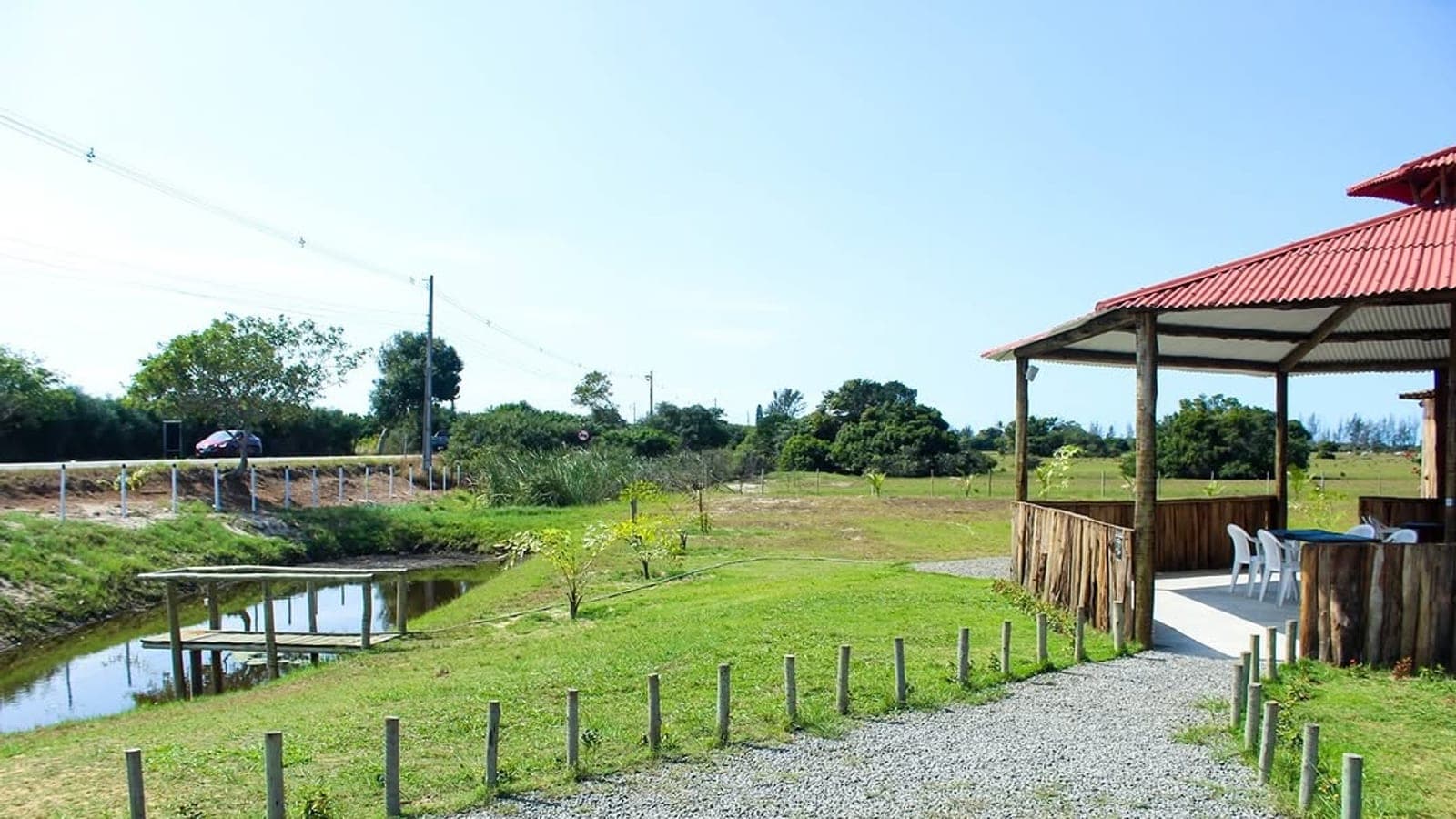 O terreno do Rancho Aroeira com o lago ao lado e o salão ao fundo